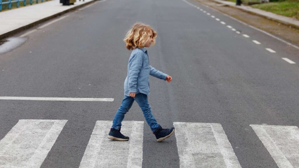 Little boy crossing alone on the road